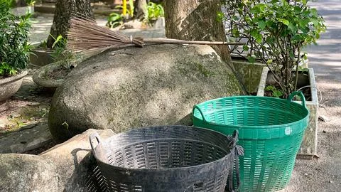 Plastic trash cans next to large rocks and a broom in a city park Stock Photos