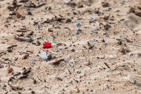 Plastic trash in sand on beach. Pollution by microplastic rubbish on coastlin Stock Photos