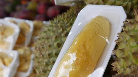 Plastic tray containing durian pulp displayed with additional durian portions Stock Footage 332789167