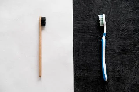 Plastic vs bamboo toothbrush on white and black background Stock Photos