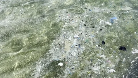 Plastic waste and microplastic debris polluting ocean water surface Stock Footage 333696956