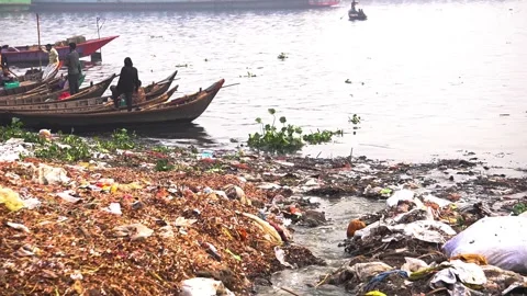 Plastic waste and pollution along riverbank with wooden boats in Bangladesh Stock Footage 345417052