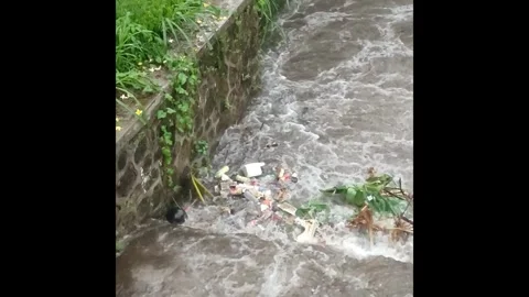 Plastic waste pollutes river during rain. Video stock 290485513