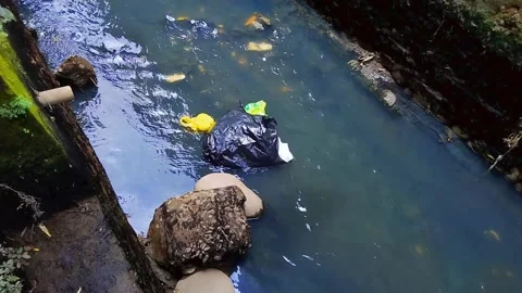Plastic waste that is thrown into a small flowing ditch 库存影片 219728346