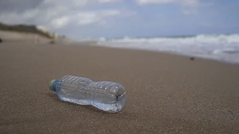 Plastic Water Bottle on Beach Washed Away by Surf Stock Footage 126067177
