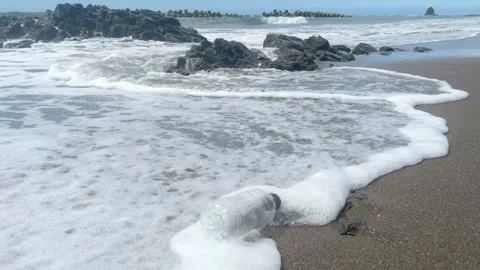 Plastic water bottle floating into sea from beach sand Stock Footage 272578424