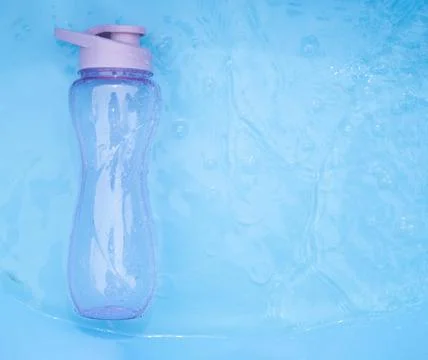 A plastic water bottle, lying on the surface of the water. Drops falling on a Stock Photos