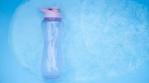 A plastic water bottle, lying on the surface of the water. Drops falling on a Stock Photos