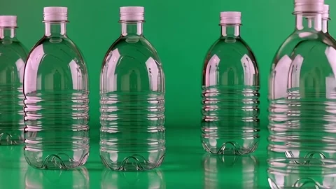 Plastic water bottles with white caps on a green background Stock Footage 317888201