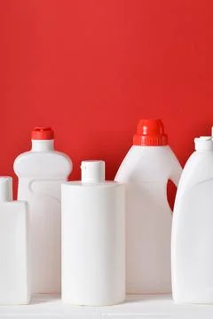 Plastic white bottles on a red background. Layout of bottles with household c Stock Photos