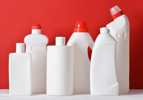 Plastic white bottles stand on a red background. Cleaning and disinfection of Foto stock