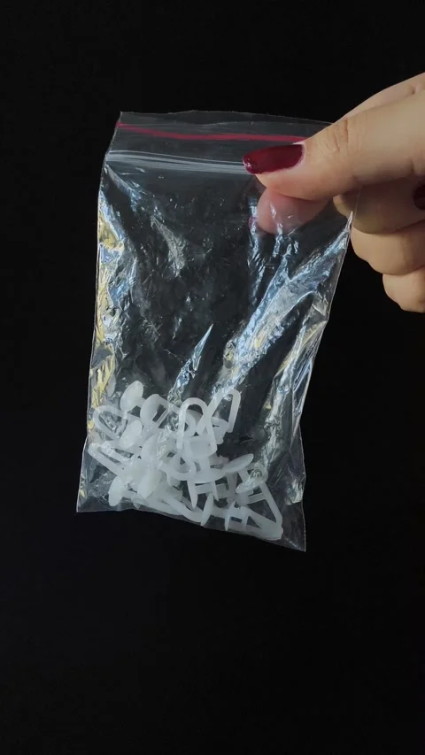 Plastic White Curtain Hooks In Zip Bag In Female Hand Close-Up on a black Stock Footage 318130273