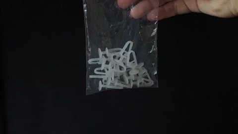 Plastic White Curtain Hooks In Zip Bag In Female Hand Close-Up on a black Stock Footage 318130447