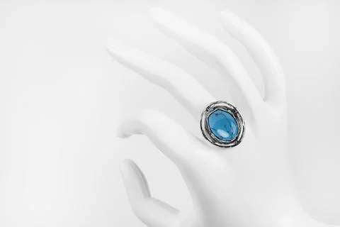 Plastic white hand with silver ring and turquoise stone on white background. 库存照片
