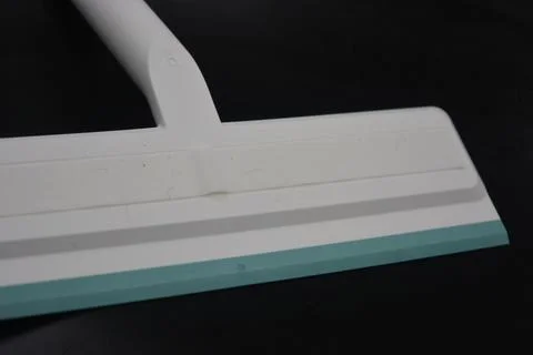 Plastic white tool, an object with a green elastic band for windows. Stock Photos