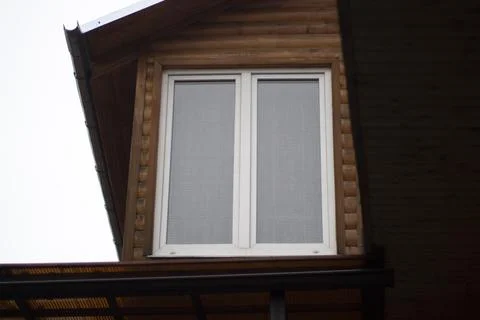 A plastic window in the house. A white window in a wooden house. Stock Photos
