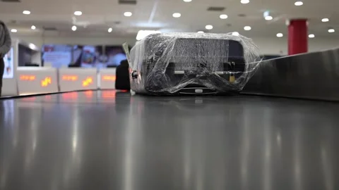 Plastic wrapped suitcase on baggage belt Stock Footage 328969031