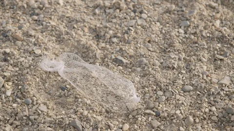Plastic wrapper litter left on a pebble beach, discarded by a lazy holidaymaker Video stock 129689499