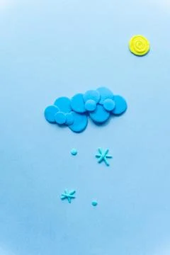 Plasticine sun with cloud. Modeling clay handmade weather on blue background. Stock Photos