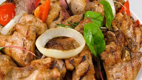 Plate of assorted grilled meat with vegetables, chicken wings, veal, pork Stock Footage 87568245