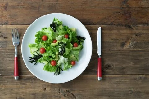 Plate with assorted vegetable salad on white plate on wooden background. Co.. Stock Photos