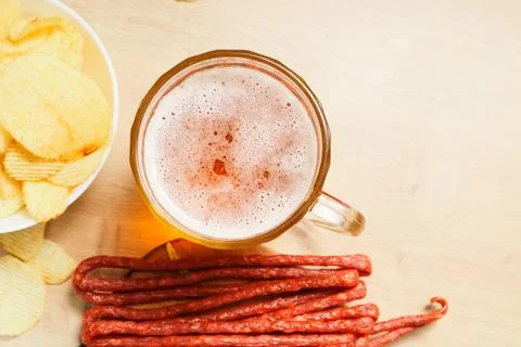 Plate with beer snacks, potatoes chips, meat sausages. Pork or beef sausage.. Stock Photos
