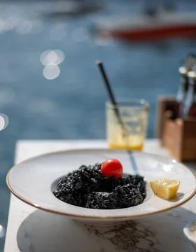 Plate of black squid ink risotto topped with a cherry tomato Stockfoto's