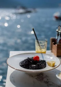 Plate of black squid ink risotto topped with a cherry tomato Stock-Fotos
