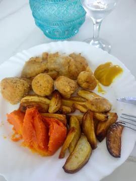 Plate with breaded chicken, rustic potatoes, and puree. Fotos de archivo