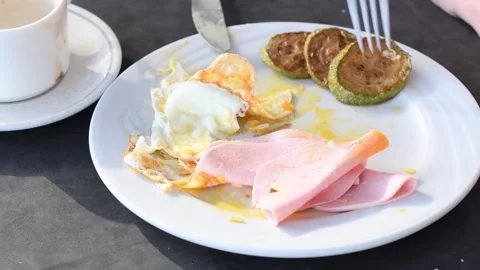 Plate with breakfast on table illuminated by morning sun, eggs, ham and zucchini Stock Footage 284989581