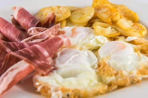 Plate of broken eggs with ham and potatoes. Stock Photos