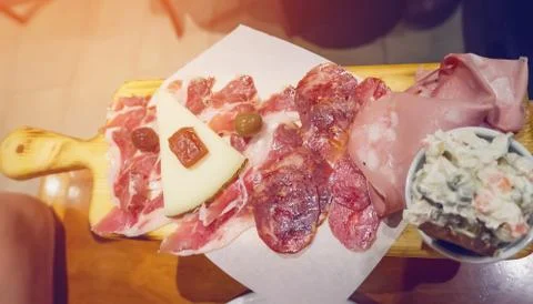 Plate in a cafe with different types of sliced deli meat and cheese with sauce. Stock Photos