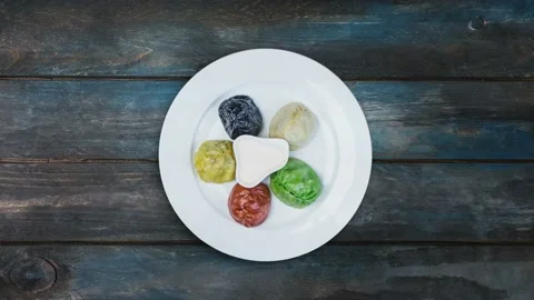 Plate with colored oriental dumplings and sauces rotates on beautiful wooden Stock Footage 128329331