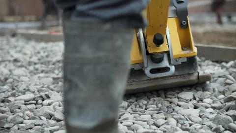 Plate compactor compacting gravel surface at construction site Stock Footage 326064518
