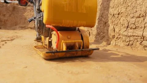 Plate compactor vibrating sand for ground leveling Stock Photos