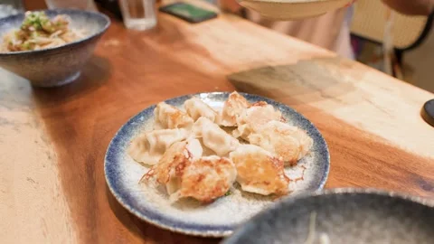 Plate of Crispy Pan-Fried Dumplings Served on Wooden Restaurant Table Stock Footage 345457876