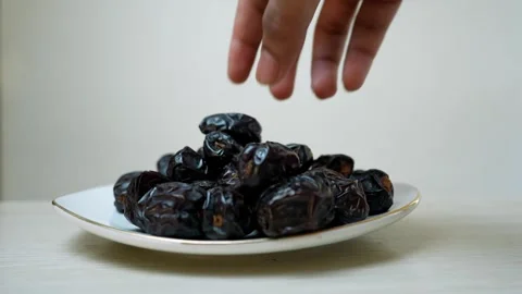 Plate of dark, glossy dates on a white surface Stock Footage 320726634