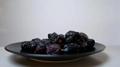 Plate of dark, glossy dates on a white surface Stock Footage 320726645
