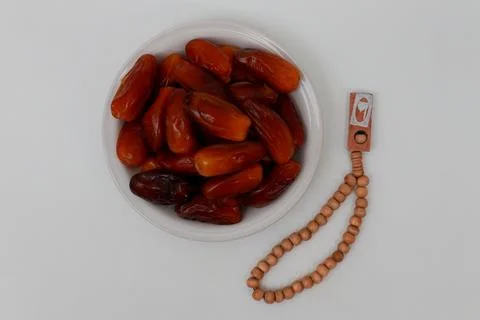 A plate of dates and prayer beads on a white background Stock Photos