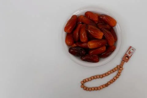 A plate of dates and prayer beads on a white background Stock Photos
