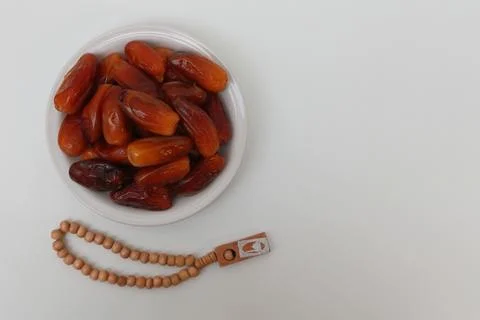A plate of dates and prayer beads on a white background Stock Photos