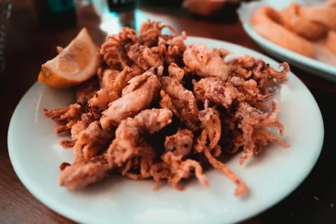 Plate of deep fried squids or Chipirones with lemon. Typical spanish tapa Stock Photos