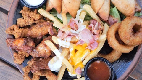 Plate with different types of hot snacks at the fresh air restaurant terrace Stock Footage 92305142