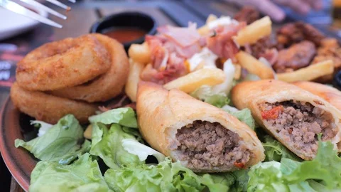 Plate with different types of hot snacks at the fresh air restaurant terrace Stock Footage 92305648