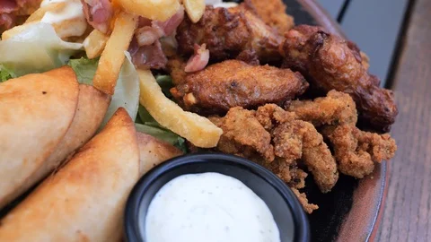 Plate with different types of hot snacks at the fresh air restaurant terrace Stock Footage 92305780
