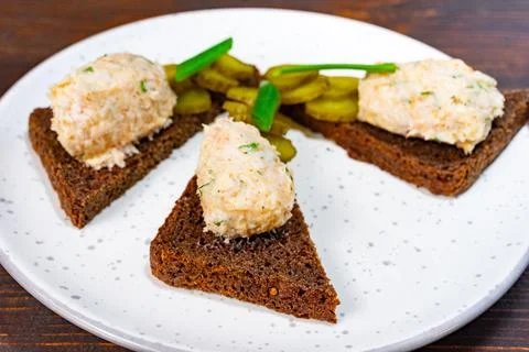 A plate displays triangular pieces of rye bread topped with a creamy spread Stock Photos