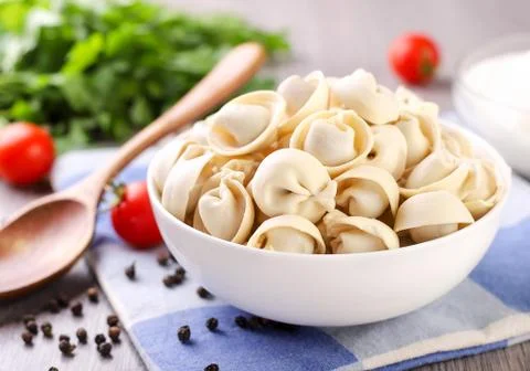 A plate of dumplings on the kitchen table with sour cream and vegetables Stock Photos