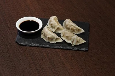 A plate of dumplings with sauce on a table Stock Photos