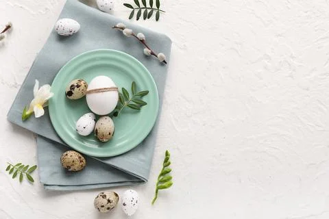 Plate with Easter eggs, leaves, beautiful flower and pussy willow branch on w Stock Photos