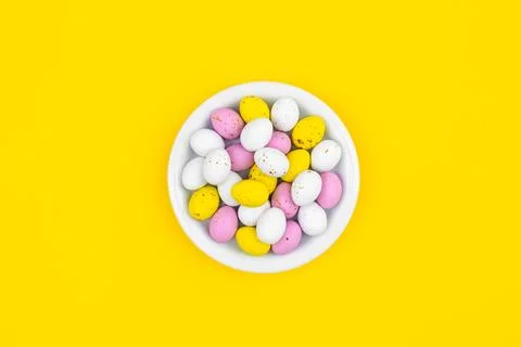 Plate with Easter eggs on a yellow background, top view. Stock Photos